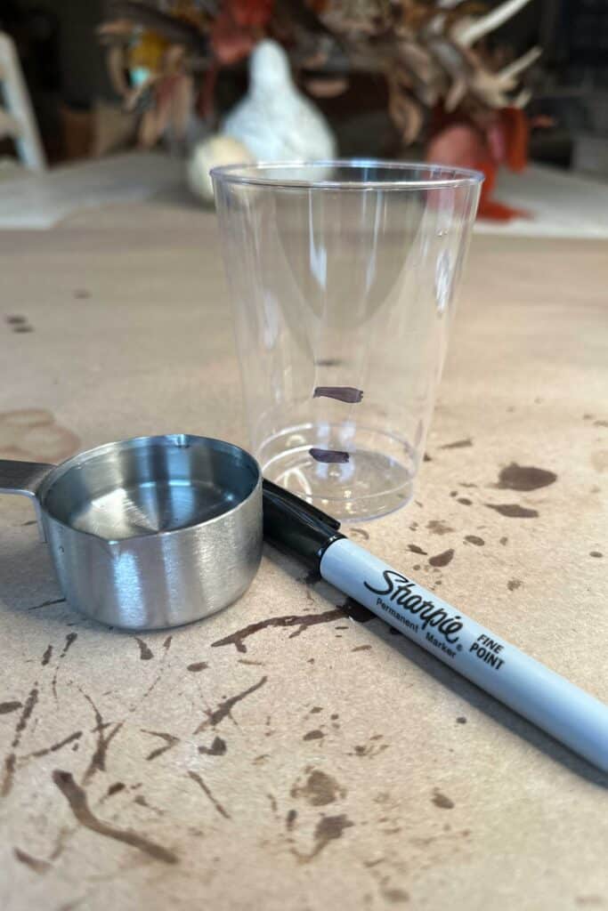 A clear cup marked with a Sharpie for exact measurements of epoxy.