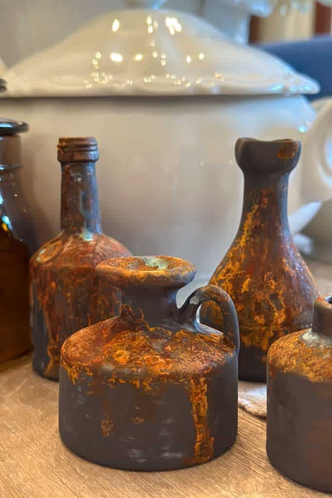 Rusty patina on mini glass liquor bottles was achieved by using a unique painting process. 