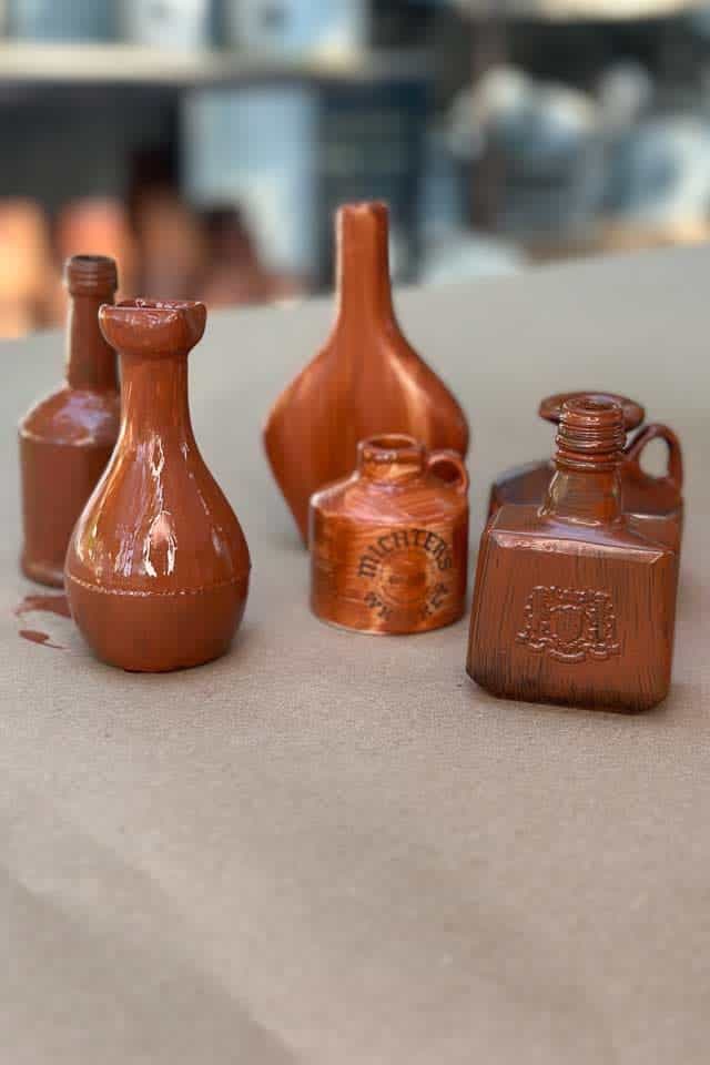 Five small bottles with a coat of primer preparing them for a rusty patina finish. 