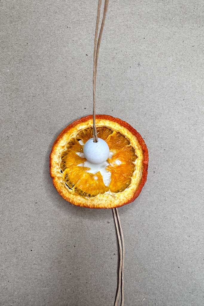 Sliced orange glued on top of the wood round with a wood bead glued on top. 