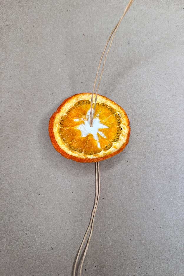 Add a slice of dried orange onto the wood disk to start your orange stack ornament. 