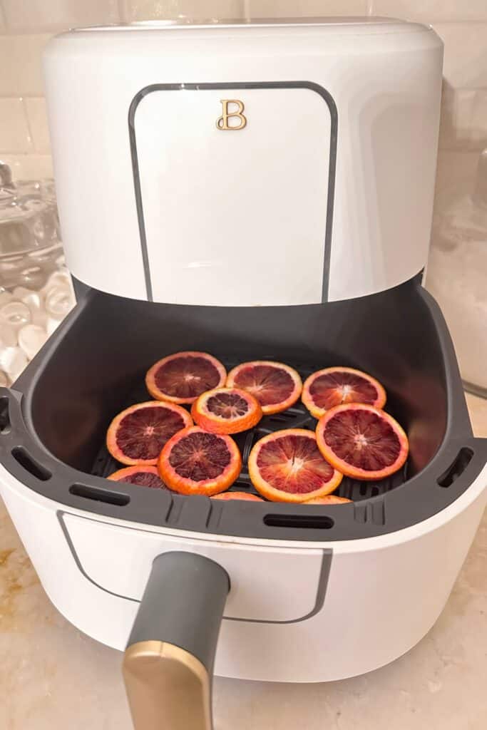 Orange slices in the air fryer getting ready to dehydrate.