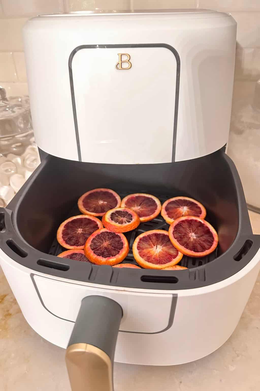 Orange slices in the air fryer getting ready to dehydrate.