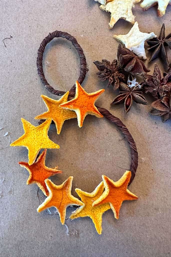 Creating a wreath ornament using small orange rind stars that have been dehydrated. 