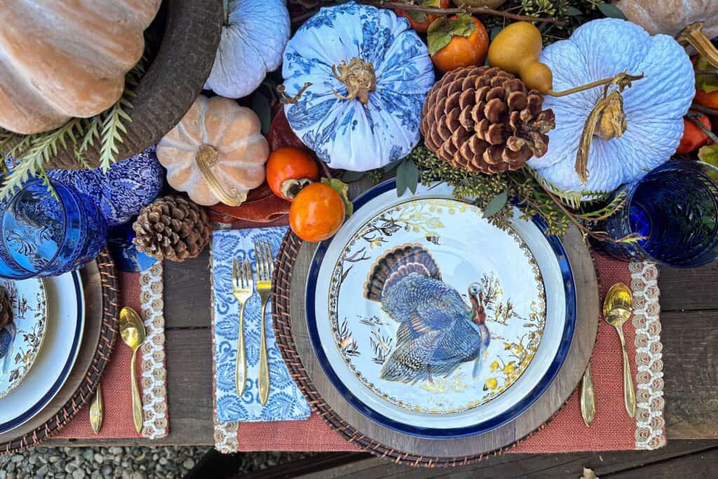 Full place setting view for Thanksgiving with the salad plate on top of the dinner plate on two chargers with gold flatware.