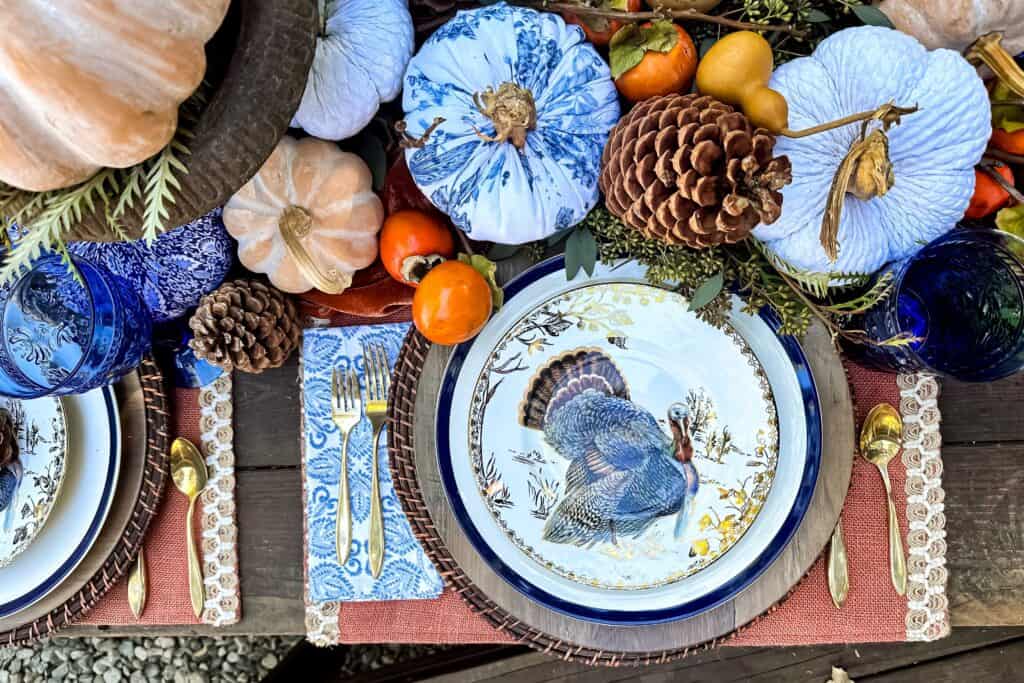 Blue and Orange Thanksgiving Table Decor Ideas-Full place setting view for Thanksgiving with the salad plate on top of the dinner plate on two chargers with gold flatware.