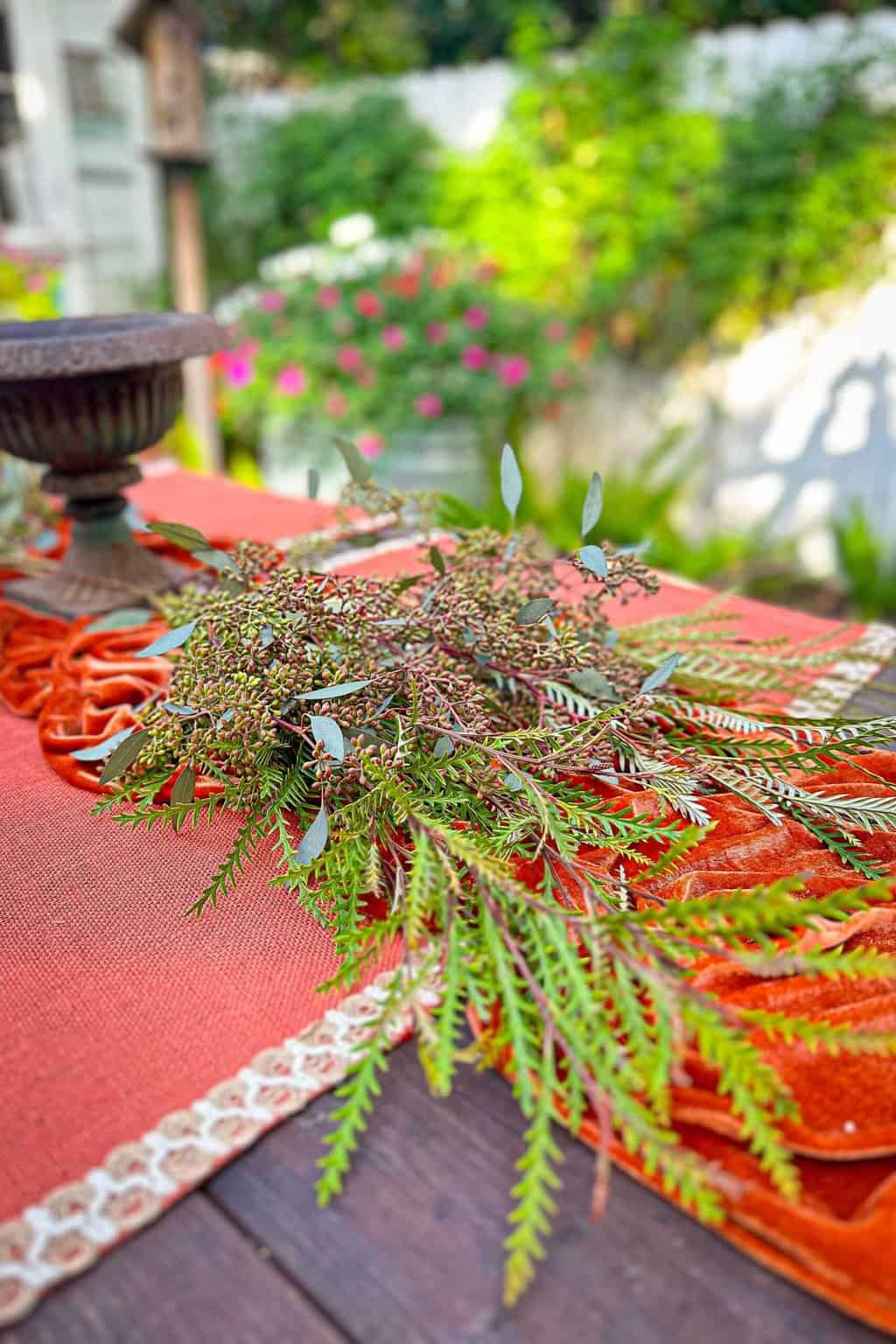 Fresh greenery as a start to creating a blue and orange tablescape for Thanksgiving.