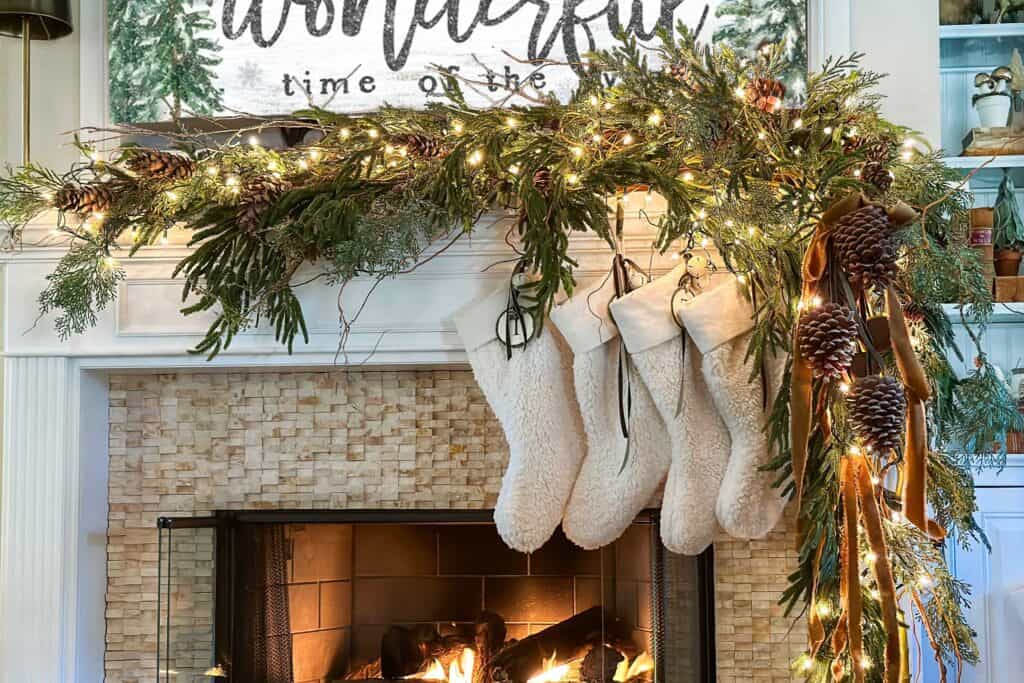 greenery and branches adorn the mantel with pinecones, stockings and velvet ribbon.