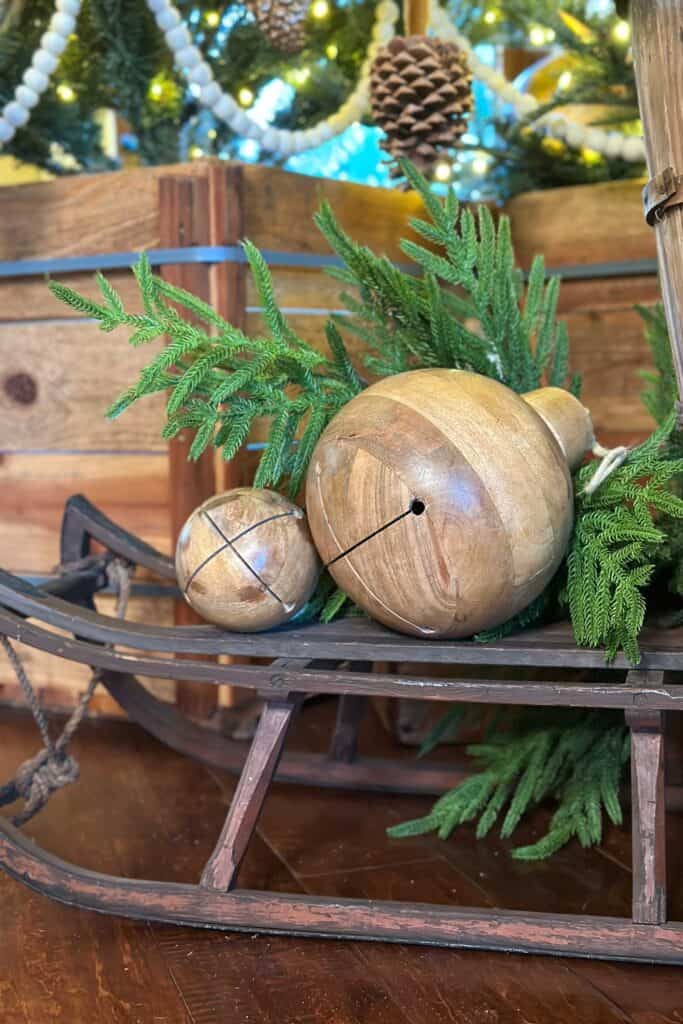 Wood Christmas jingle bells sitting on a wooden sled in front of the tree