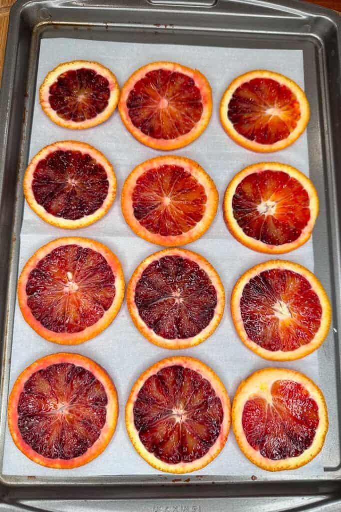 Blood orange sliced on parchment paper and a cookie sheet, ready to go in the oven.