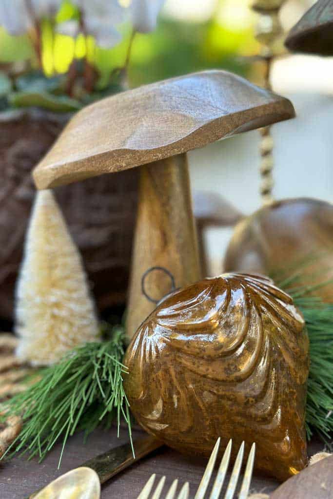 A large wooden mushroom sits among a few bottle brush trees and ornaments for my rustic table setting.