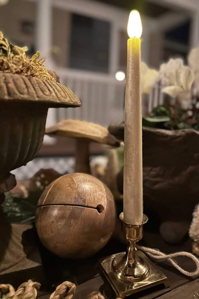A wooden bell and a gold candle sit amongst the table decor for a rustic Christmas tablescape.