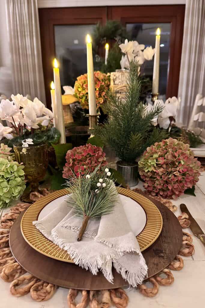 Rustic indoor table setting for Christmas. fresh hydrangeas, white cyclamen, wood charger plates, and gold and white dinner plates for a fresh and easy decor.