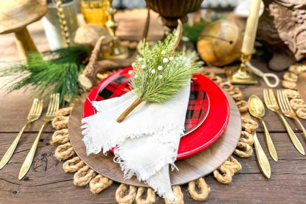 Table place setting with red and buffalo plaid plates on a rustic table for Christmas.