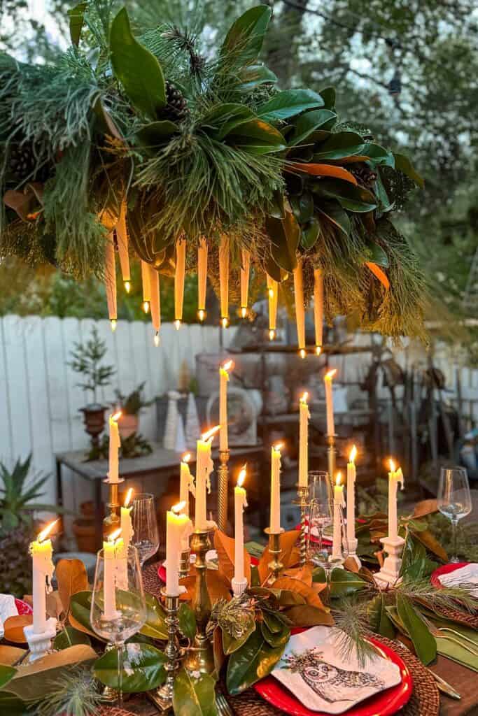 Christmas tablescape with a hanging chandelier with many candles on the table.