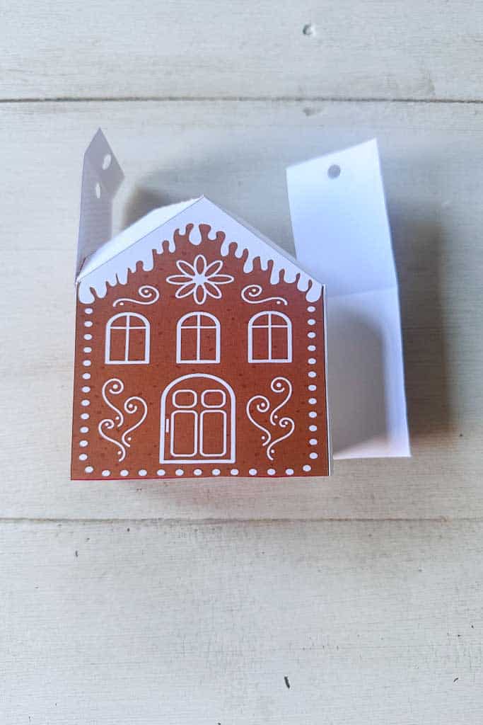 The printable gingerbread house is lying on the table in the process of getting put together.