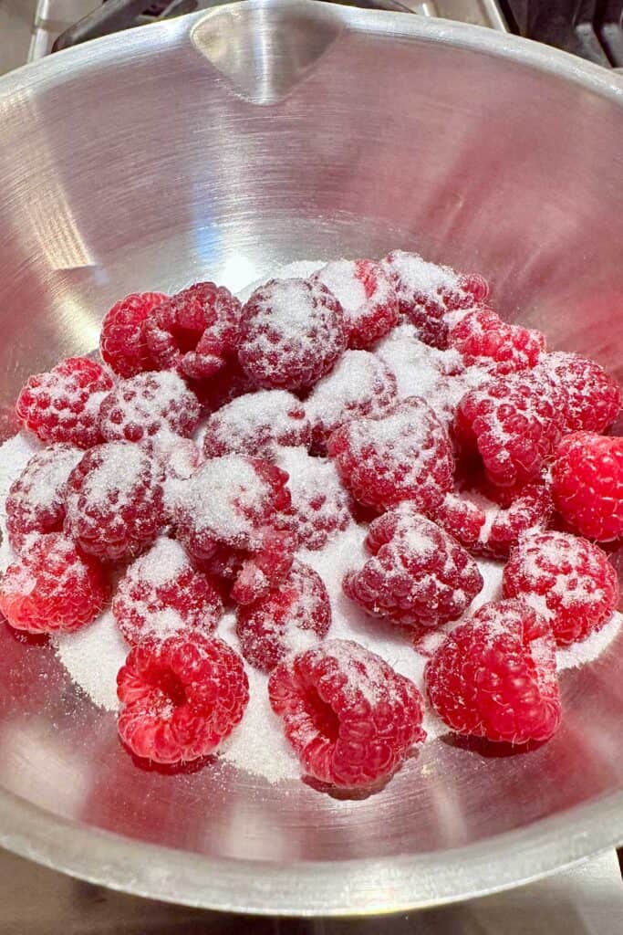 FRESH RASPBERRIES, SUGAR, AND WATER IN A PAN TO MAKE A RASPBERRY PUREE TO POUR OVER THE BUTTER CAKE.
