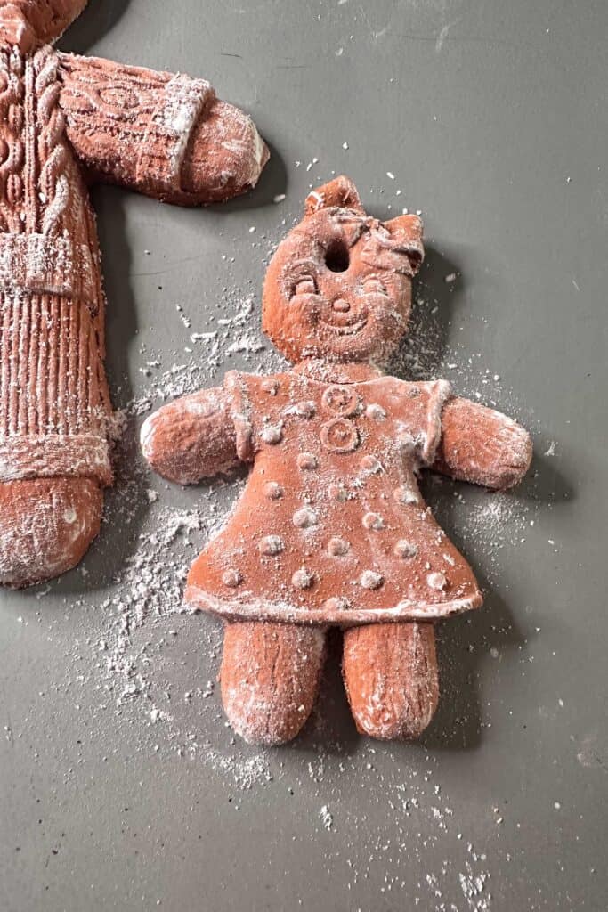 Air dry clay gingerbread girl ornament laying on a cookie sheet to dry.
