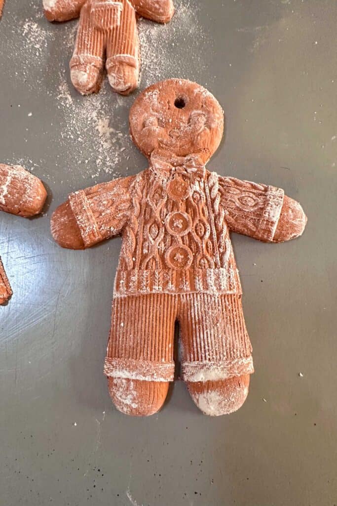 Air-dried clay gingerbread man ornament drying on a cookie sheet.