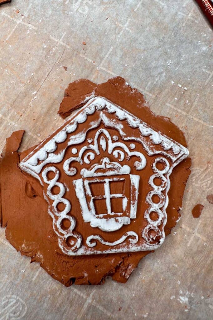 A gingerbread house ornament is taken out of the mold and ready to be trimmed.