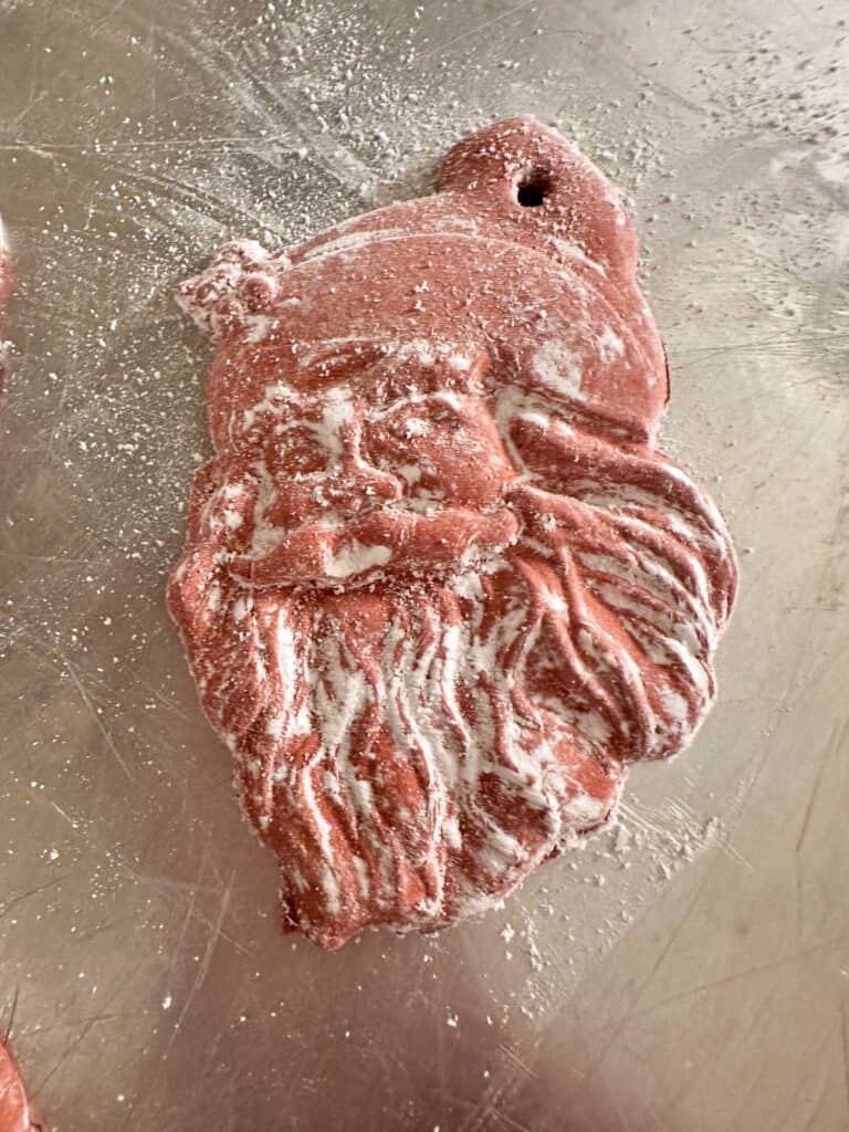 Santa air dry clay ornament coming out of the mold with cornstarch on it.