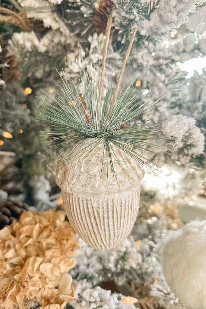 A large white acorn ornament with a touch of greenery on the top. 