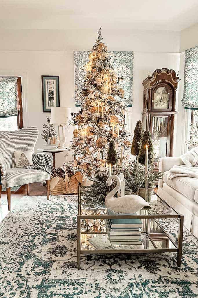 A BLUE AND WHITE LIVING ROOM WITH A NATURAL THEMED CHRISTMAS TREE WITH DRIED HYDRANGEAS, CANDLES, RUSTY BELLS AND MORE. 