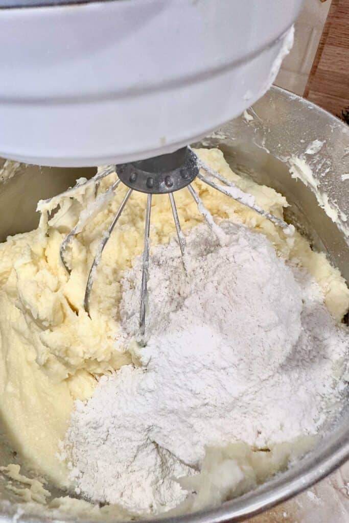 Mixing the butter cake batter while adding the flour mixture.