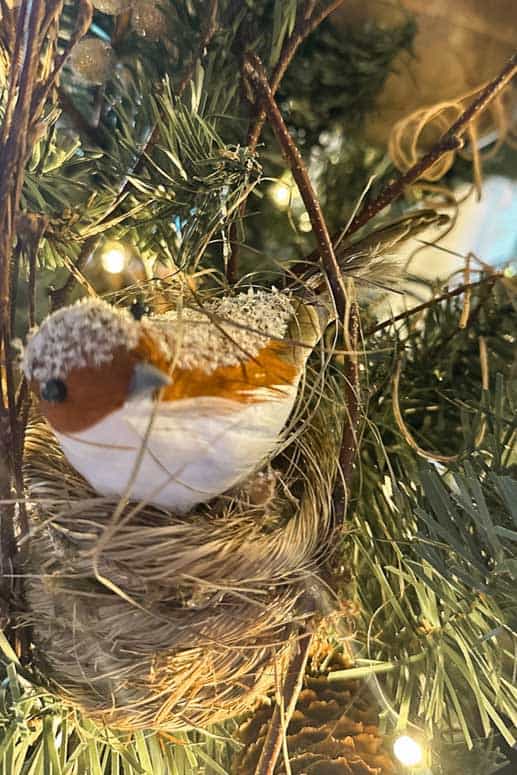 Bird in a bird nest hanging on the Christmas tree. 