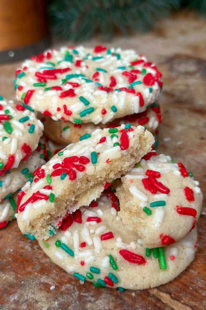 Cookies with red and green sprinkles sitting on a cutting board.