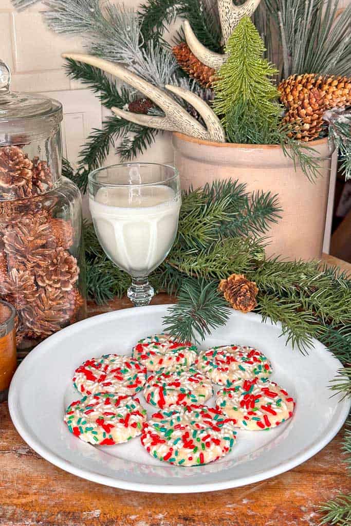 Sprinkle Christmas sugar cookies on a plate with a glass of milk. 