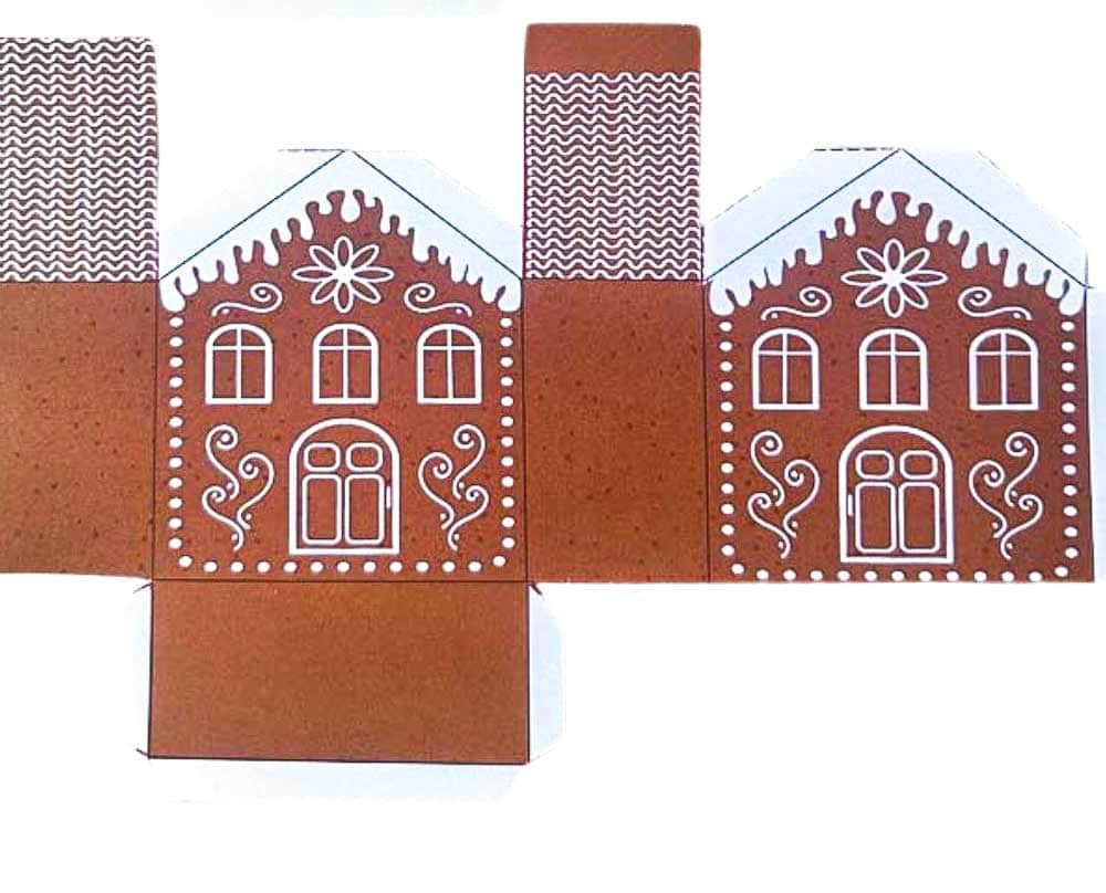 Paper gingerbread houses cut out and lay flat on a table before putting them together.