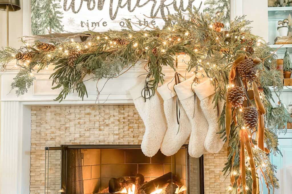 The family room mantel has greenery, curly willow branches, pinecones, and natural stockings. 