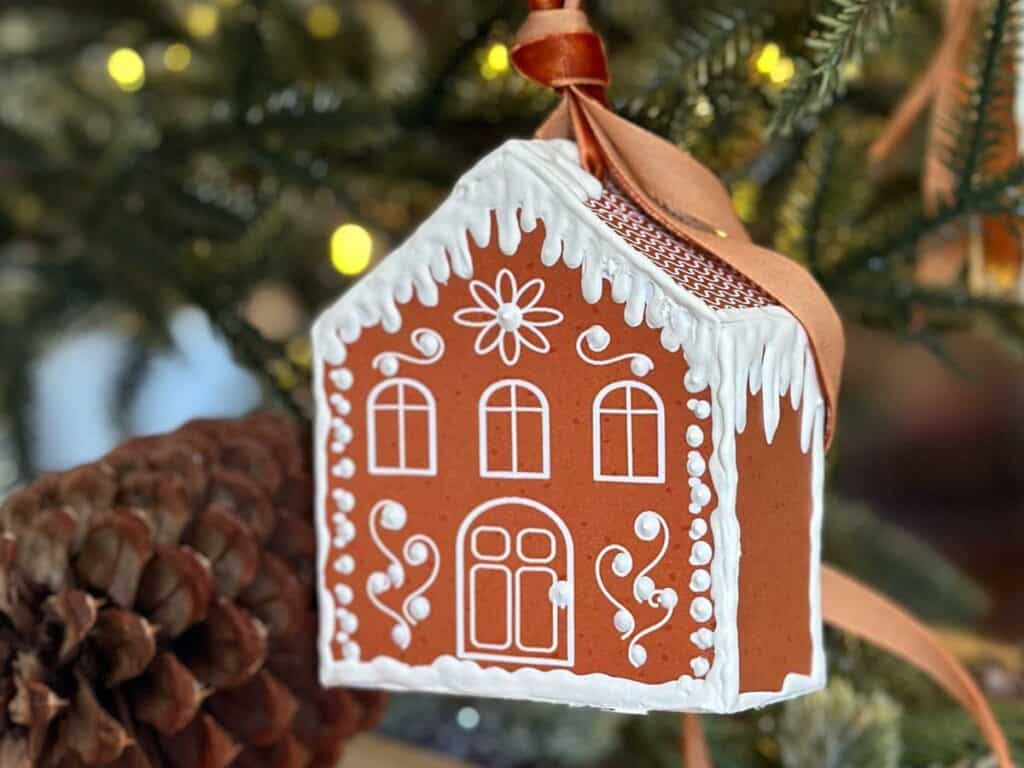 A 3D gingerbread house printable ornament is hanging on the Christmas tree.