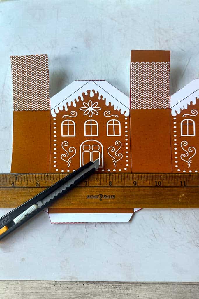 A paper gingerbread 3D house shows where to score the lines for folding.