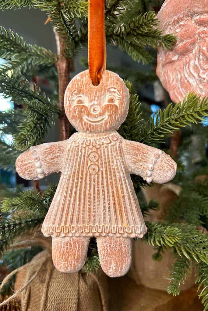 An air-dried clay gingerbread girl Christmas ornament hanging on the tree.