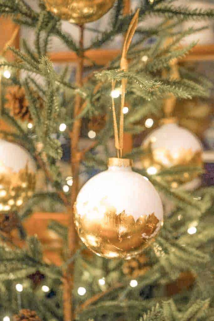 Gold and white ornaments are hanging on a Christmas tree.