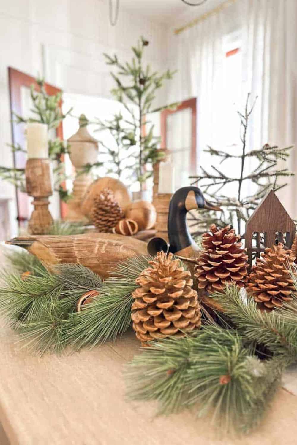 A wood goose, pinecones and greenery adorn the dining room table for the holidays. 