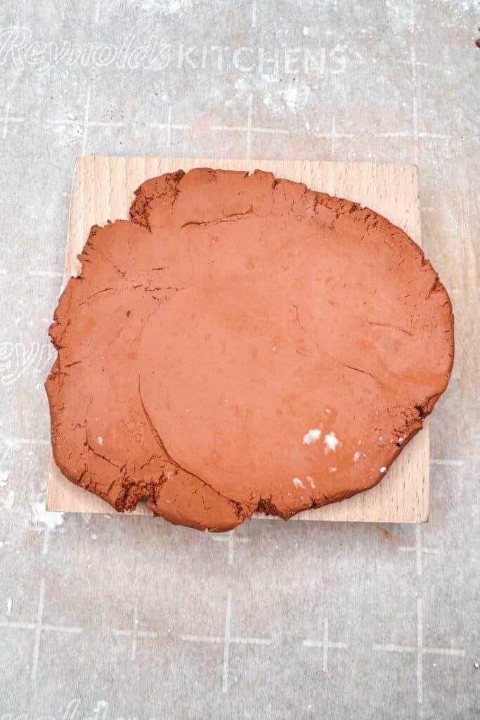 Air dry clay on top of a wooden cookie mold before pressing it into the mold.