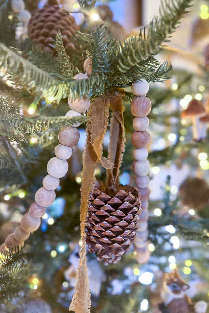 Pinecones with velvet ribbon and wood beaded garland hanging in the Christmas tree. 