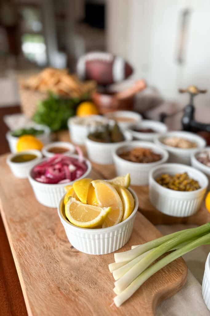 Nacho bar set up for a football game, including sliced lemons, onions, meat, and other toppings.