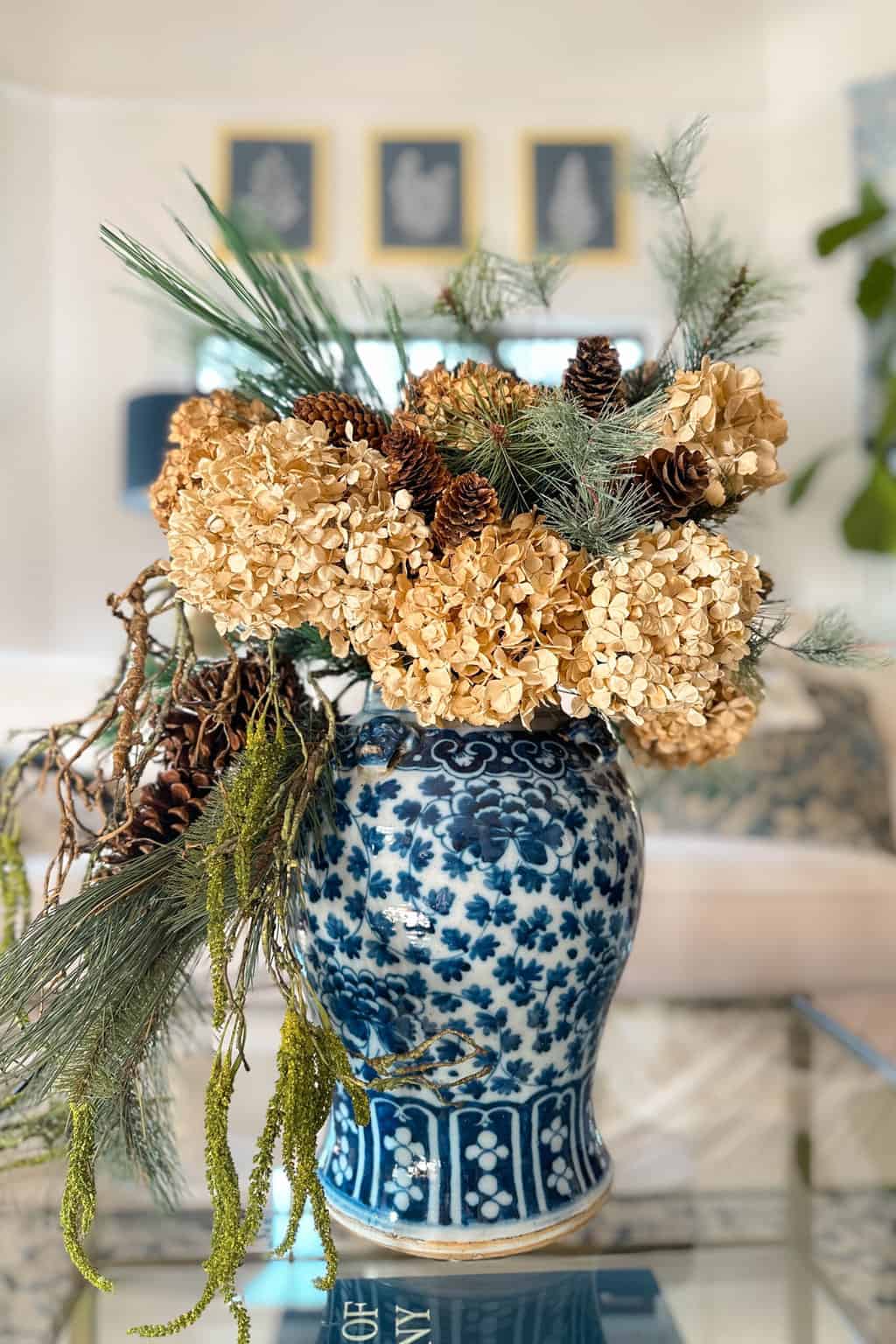 Winter decor that is not Christmas- A floral arrangement of dried hydrangeas, greens, and pinecones in a vintage blue and white vase.