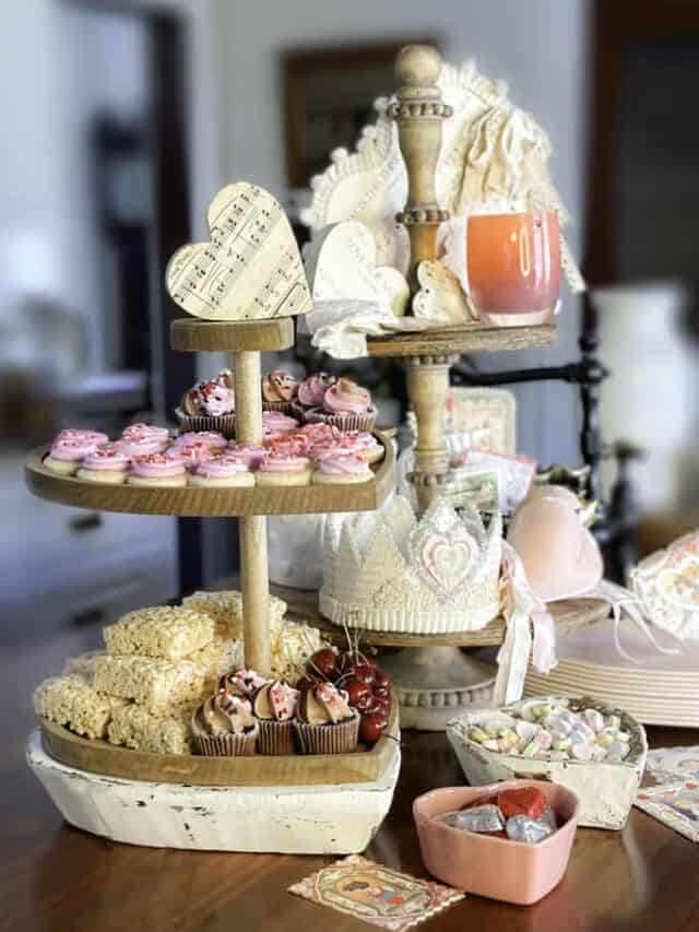 Two-tiered trays styled for Valentine's Day. One is full of fun and colorful decorations to celebrate Valentine's day, while the other tray is full of yummy treats for the holiday.