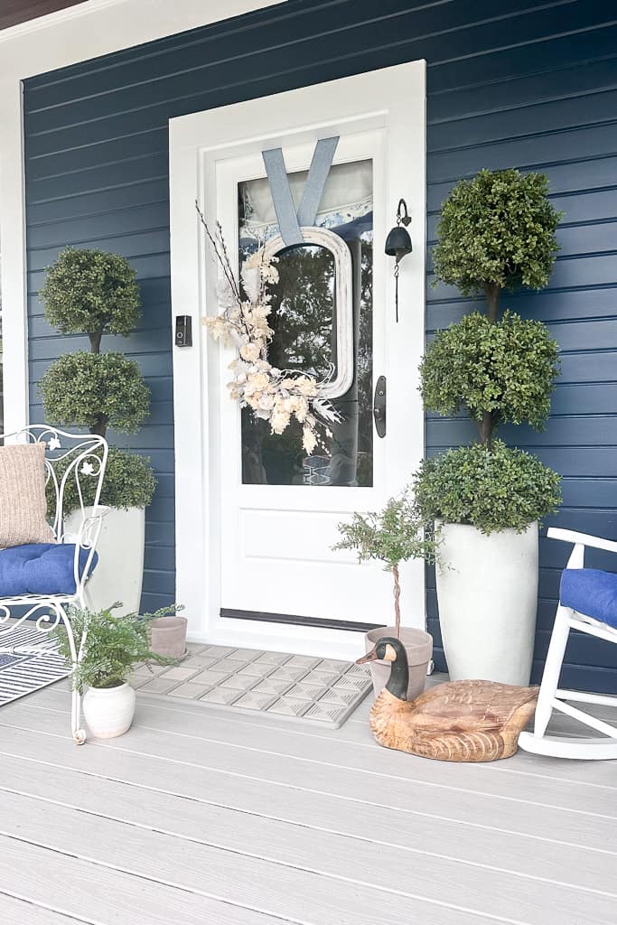 Front door with Outlier door mat. Topiaries flank the front door with a beautiful white wreath.
