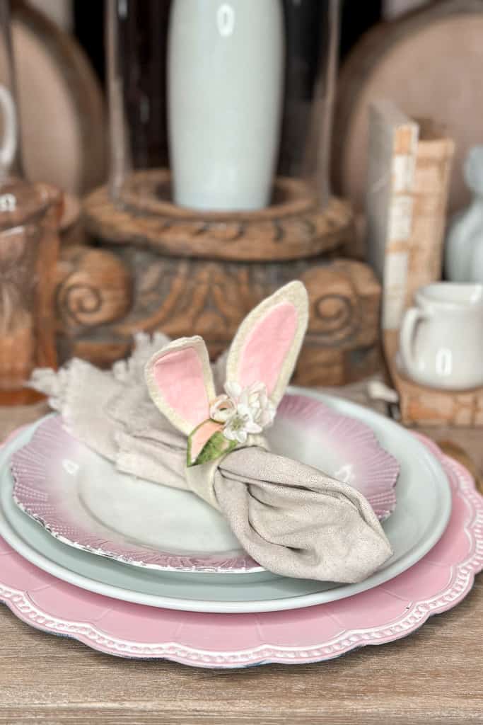 Diy flower bunny ear napkin ring sitting on a place setting on the table. 
