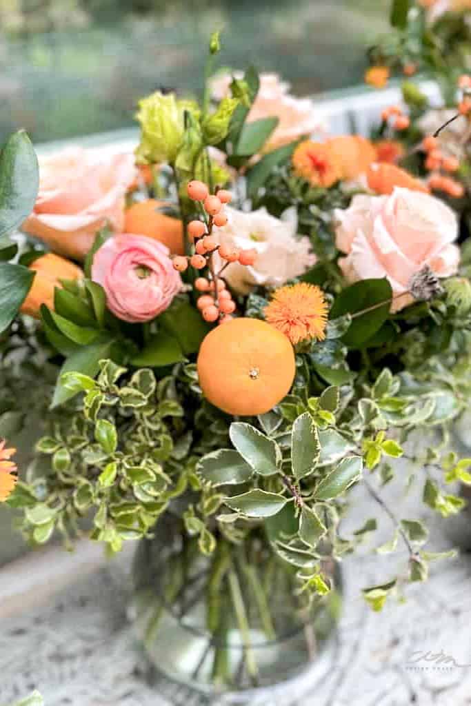 Floral arrangement with greens and orange flowers with little cuties.