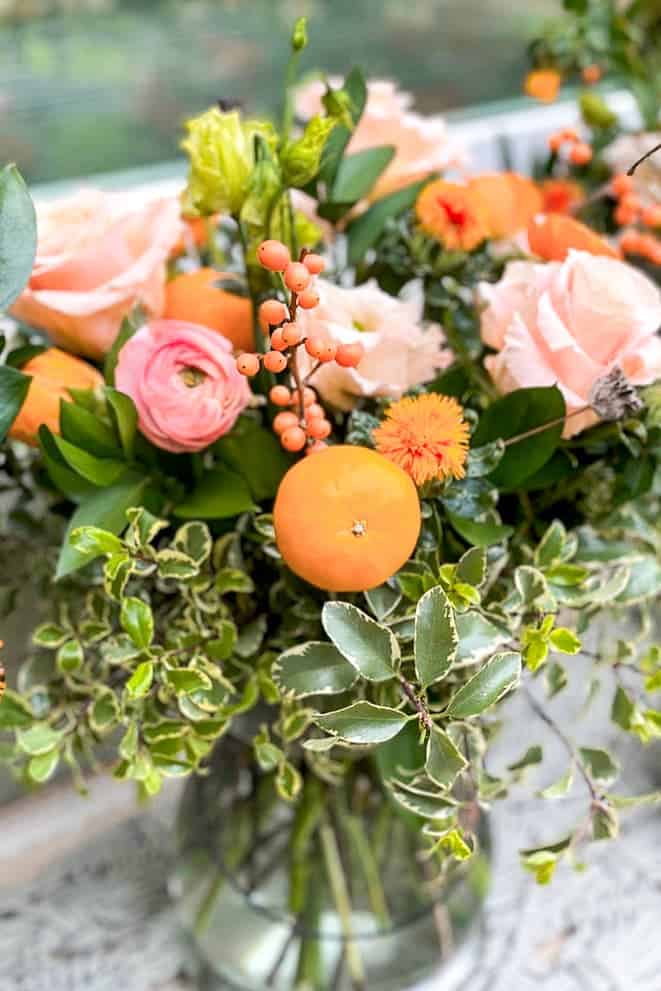 Floral arrangement with greens and orange flowers with little cuties.