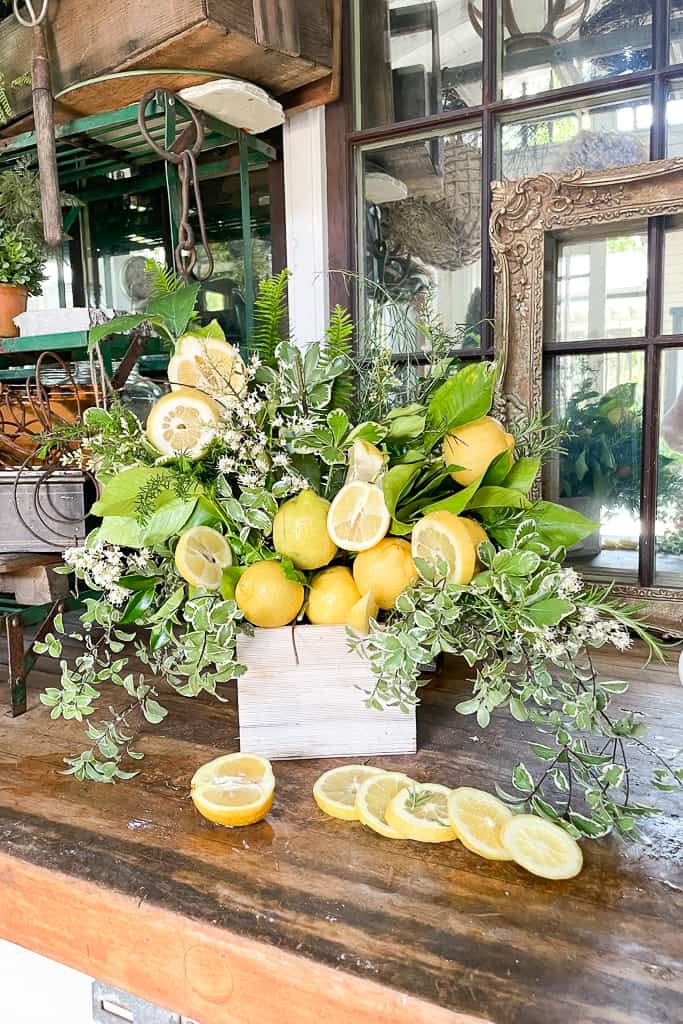 Lemon flower arrangement sitting on the workbench with sliced lemons. 