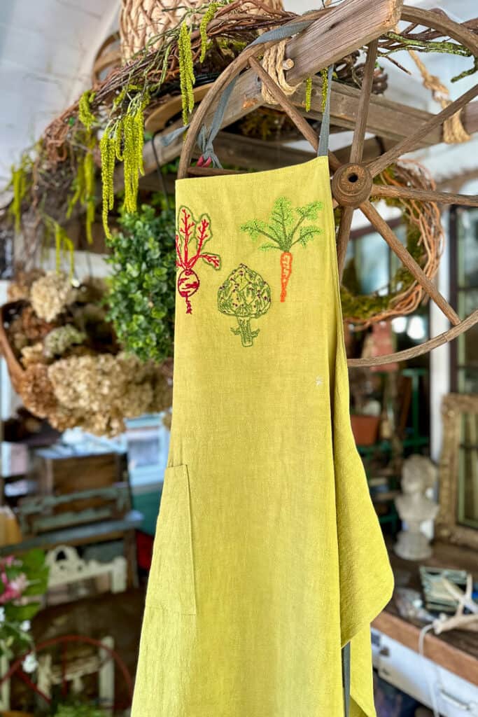 Finished embroidered  veggies on an apron hanging in the shed, 