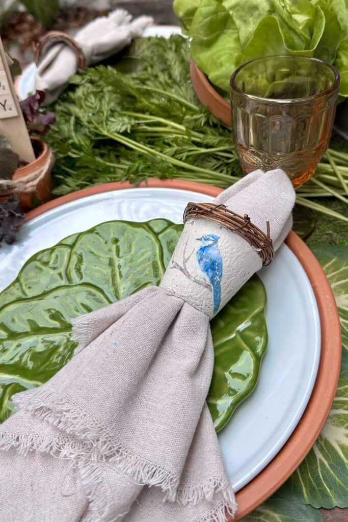 DIY peat pot napkin rings are housing a linen napkin on a green cabbage plate for the garden party. 